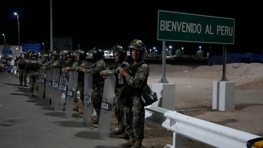 An image of Peruvian police with shields lined up next to a sign that says 'Bienvenido al Peru' 