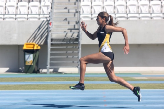 Ella Pardy runs along an athletics track.