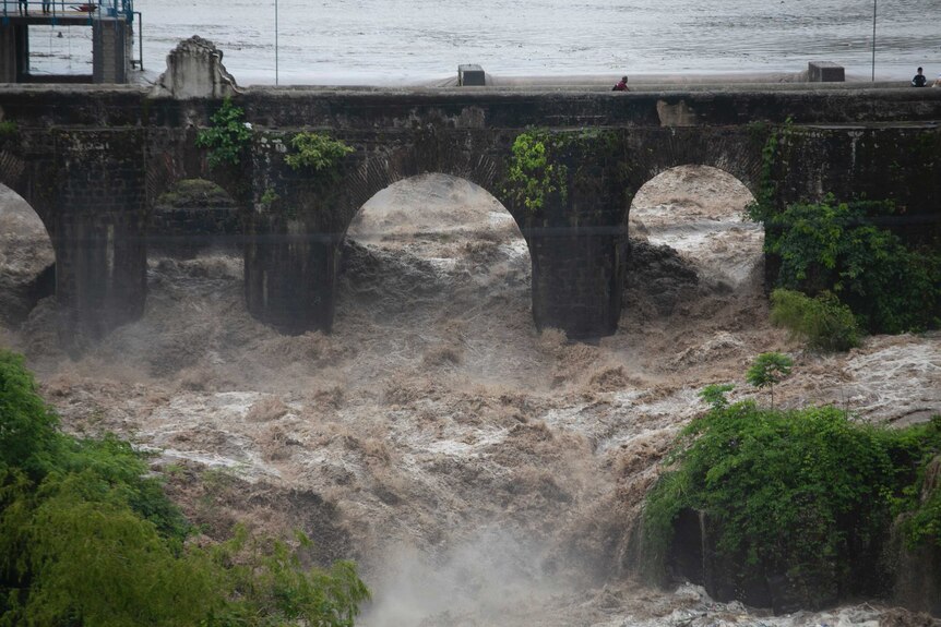The swollen Los Esclavos River flows violently under a bridge during tropical storm Amanda.