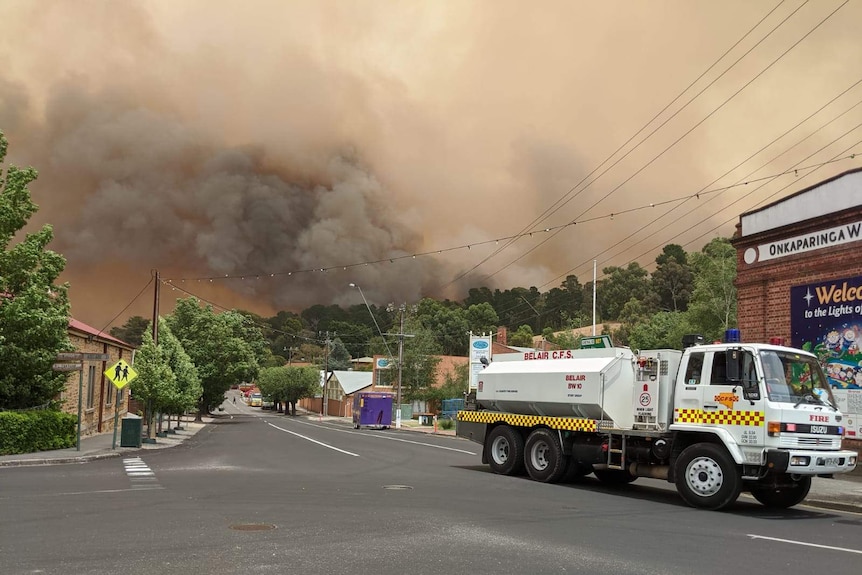 A Country Fire Service truck parked on a street in Lobethal with thick smoke bellowing above the town