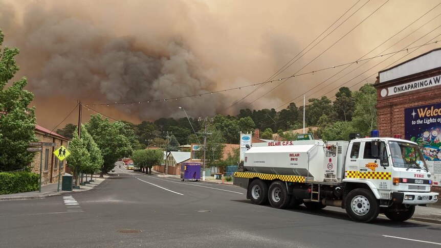 A Country Fire Service truck parked on a street in Lobethal with thick smoke bellowing above the town