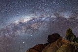 A night sky with rocks in the foreground.