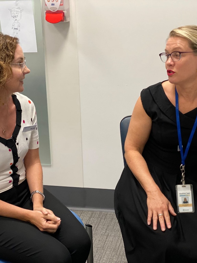 Speech pathologist Nicole Amos speaking with Doctor Heidi Webster at a hospital.