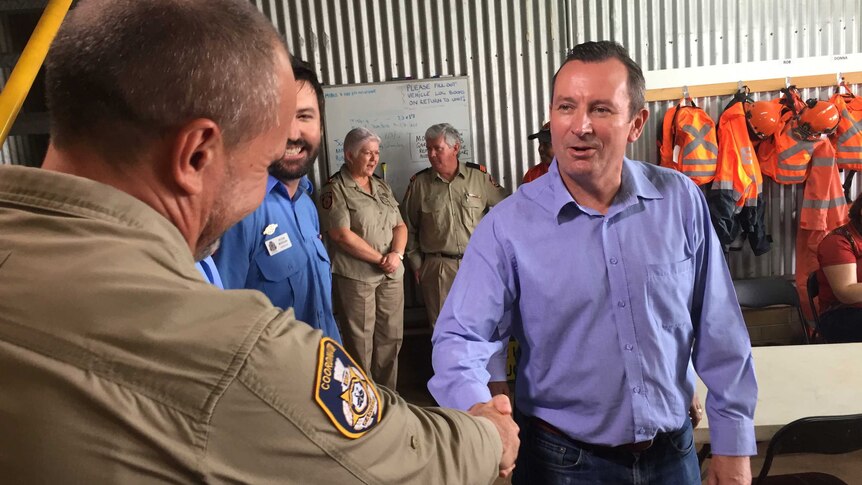 WA Premier Mark McGowan shakes the hand of an emergency services worker as others look on.