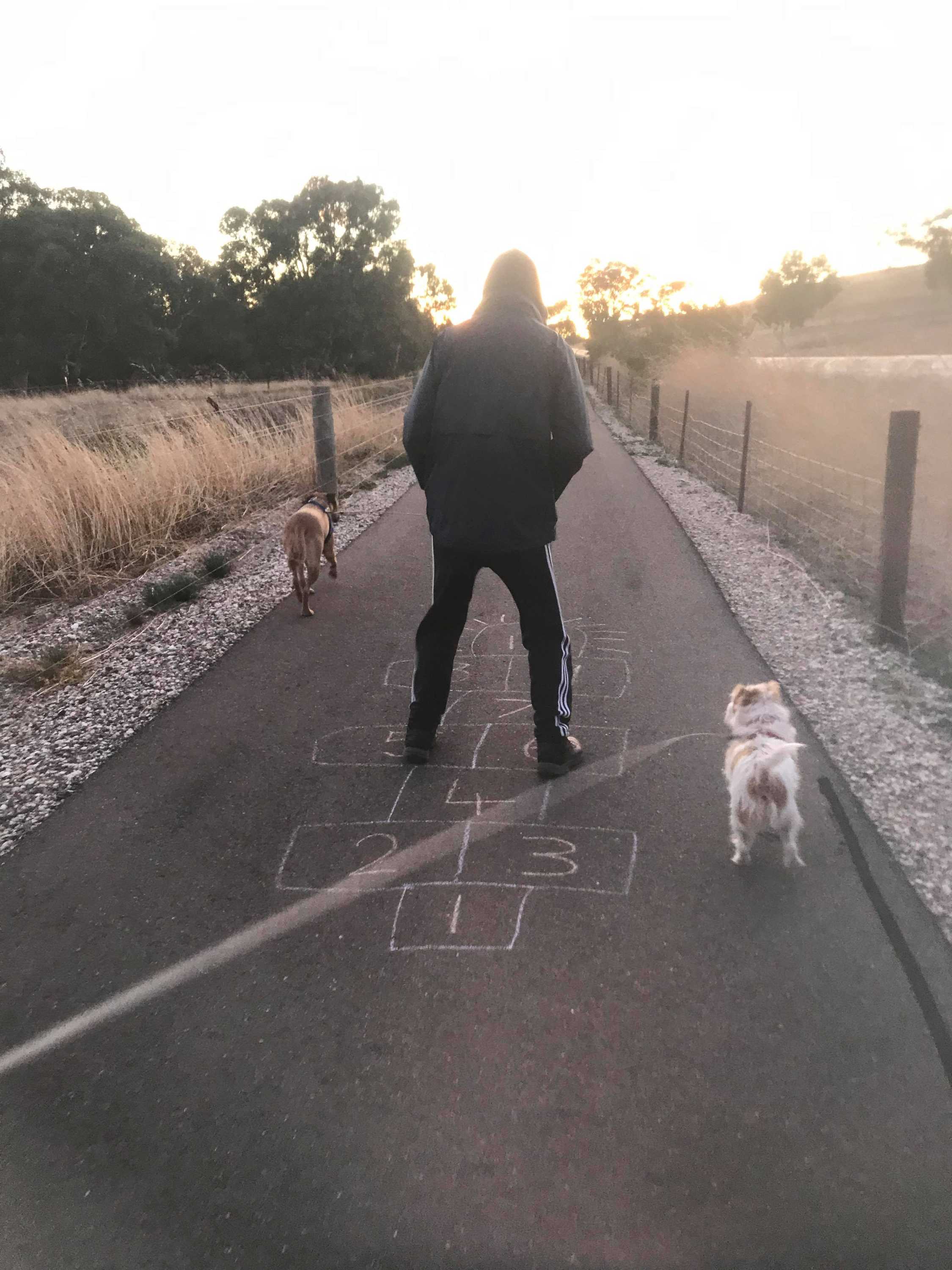 A man jumps on chalk-drawn hopscotch at sunrise.