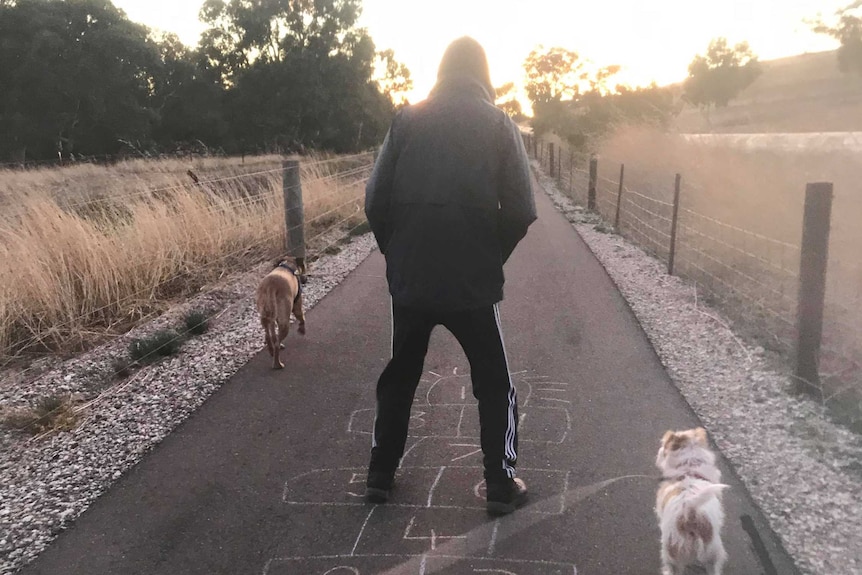 A man jumps on chalk-drawn hopscotch at sunrise.