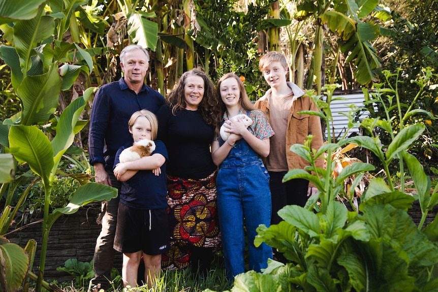 A family portrait in a leafy garden with two guinea pigs. 