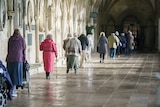 A line of people queue for vaccinations at a cathedral entrance