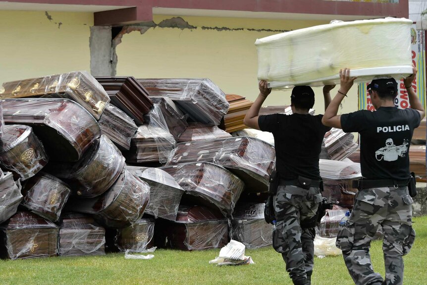 Police officers pile empty coffins after an earthquake