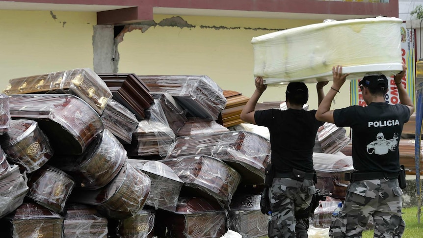 Police officers pile empty coffins after an earthquake