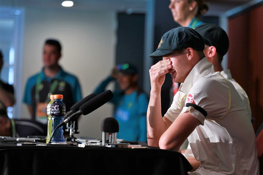 Steve Smith covers his face with his hand as he laughs during a press conference at the Gabba.