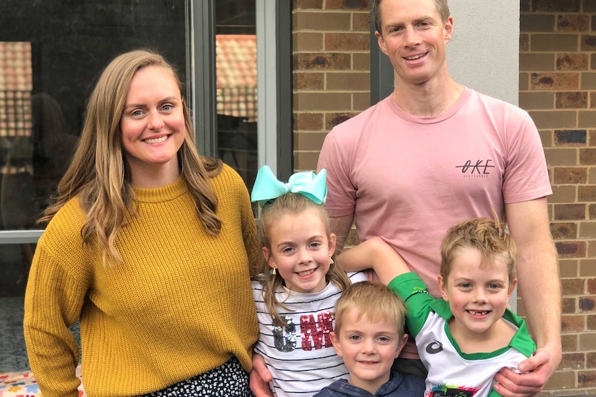 The Camm family stand outside their home.