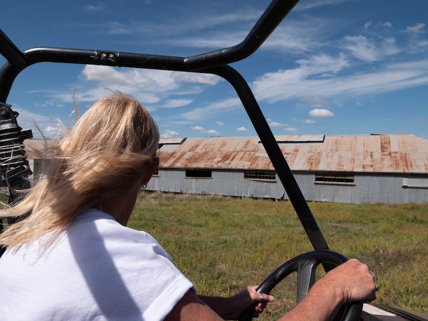 A woman looks at an old building from her quad bike.