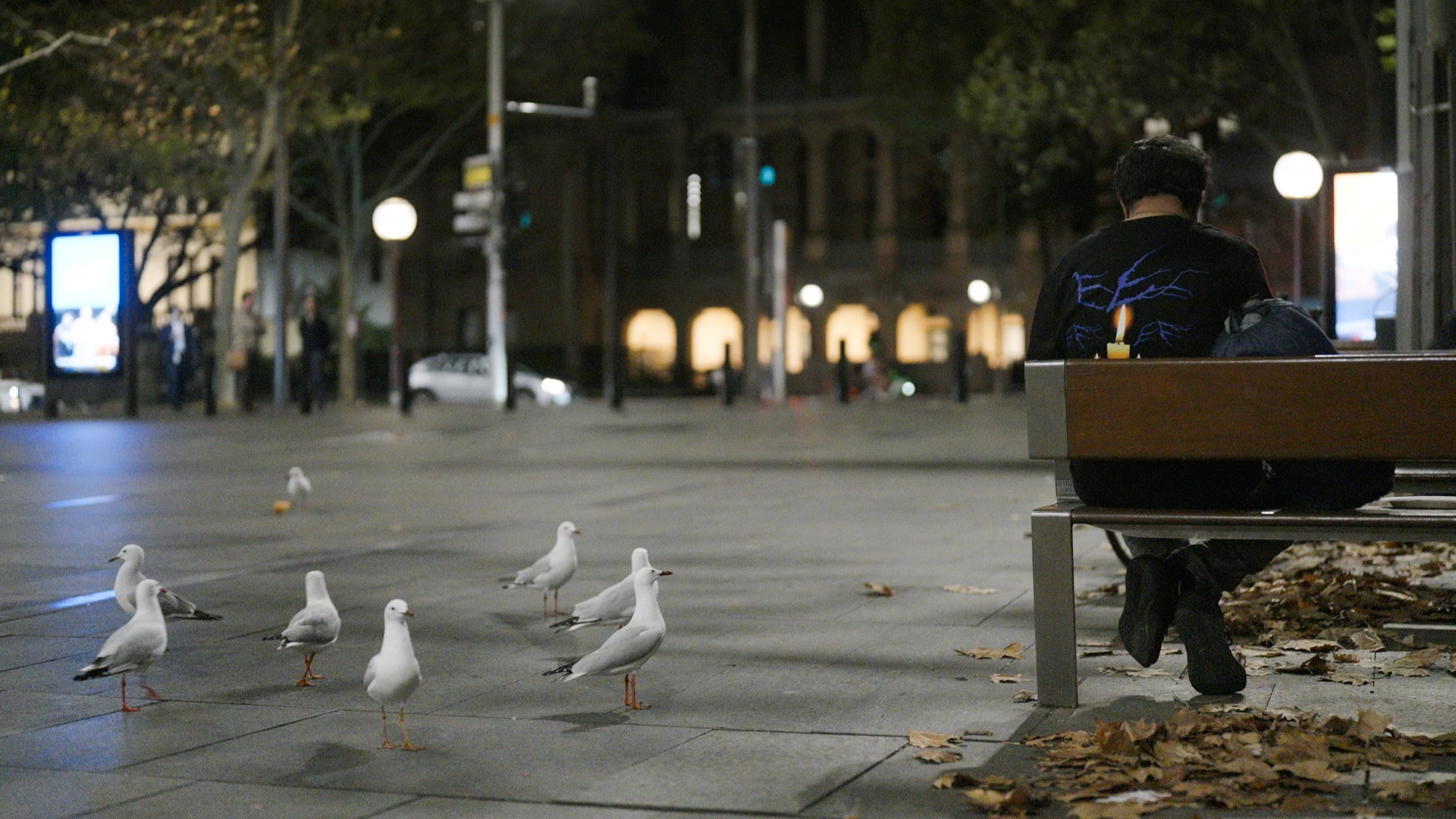 A man sitting outside on a park bench at night.