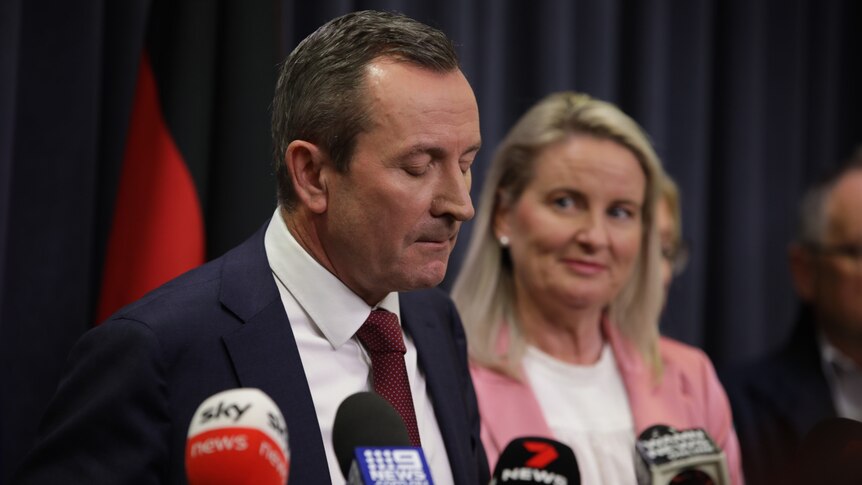 A close-up shot of WA Premier Mark McGowan speaking at a media conference indoors in front of a blonde woman.
