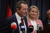 A close-up shot of WA Premier Mark McGowan speaking at a media conference indoors in front of a blonde woman.