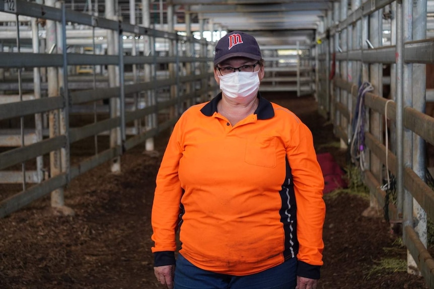 Bullsbrook resident Sharleen Hall, wearing a mask, stands among horses' stalls at an evacuation point.