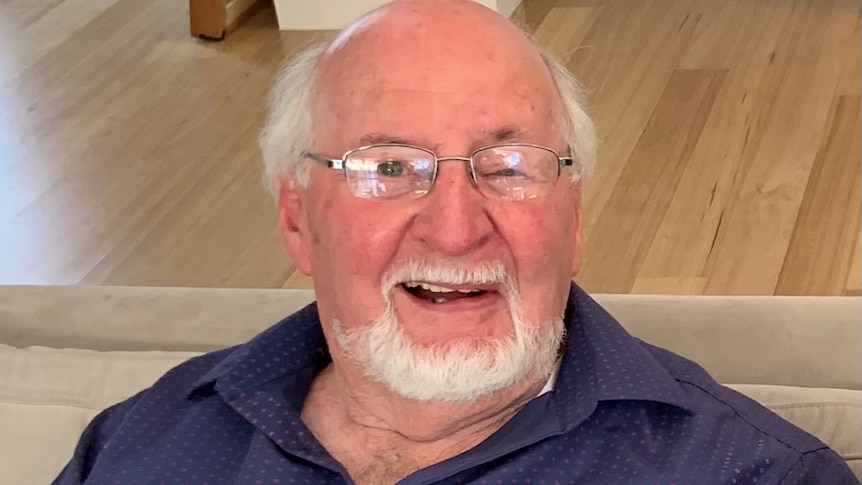 A photo of an older man smiling while wearing glasses