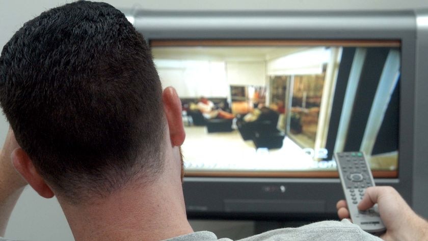 A man watches TV while sitting in a lounge chair