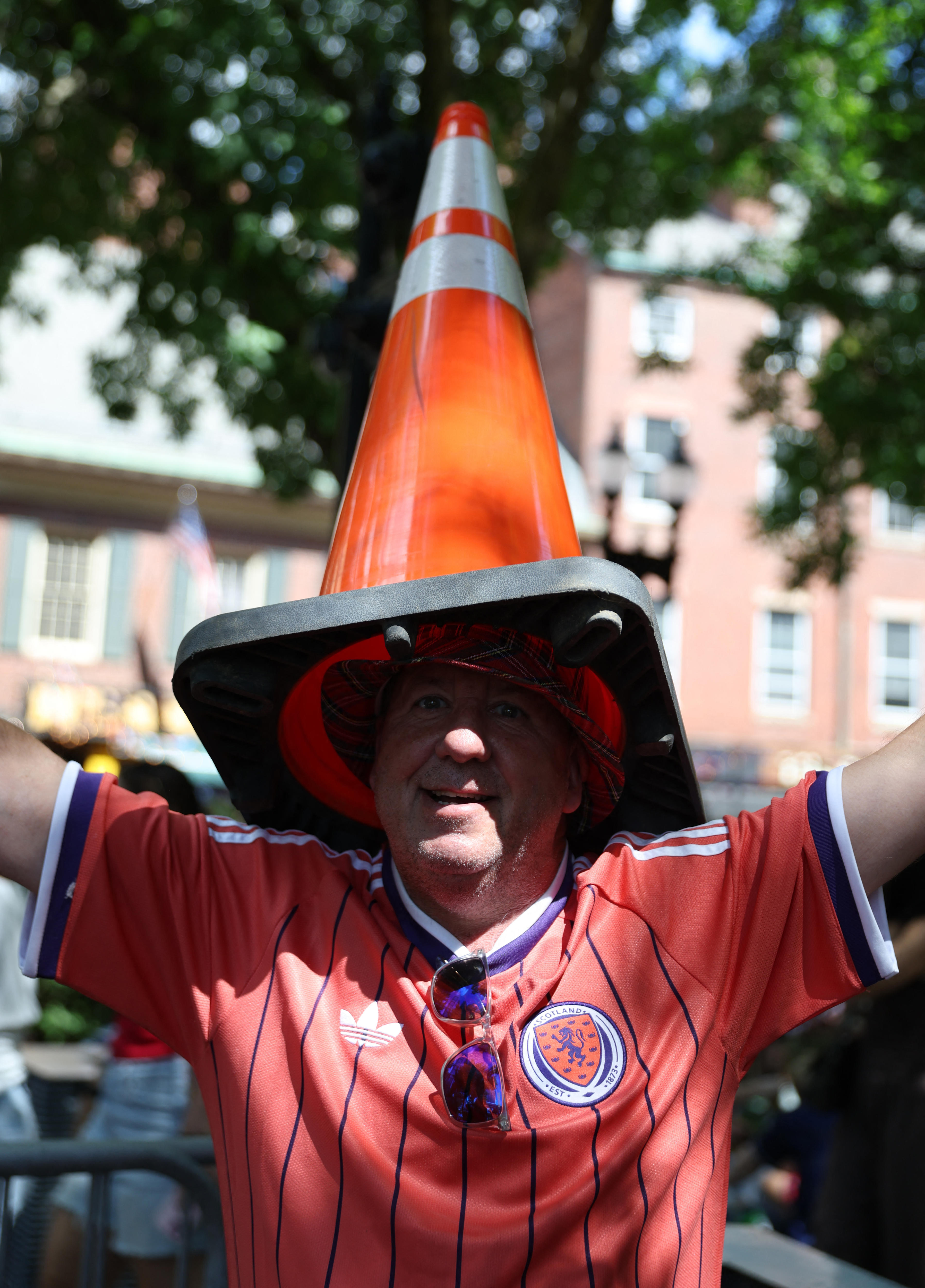 A man wearing a red Scotland jersey and a orange traffic cone on his head