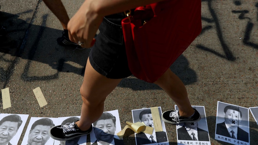 A person walks on the ground littered with portraits of Chinese President Xi Jinping.