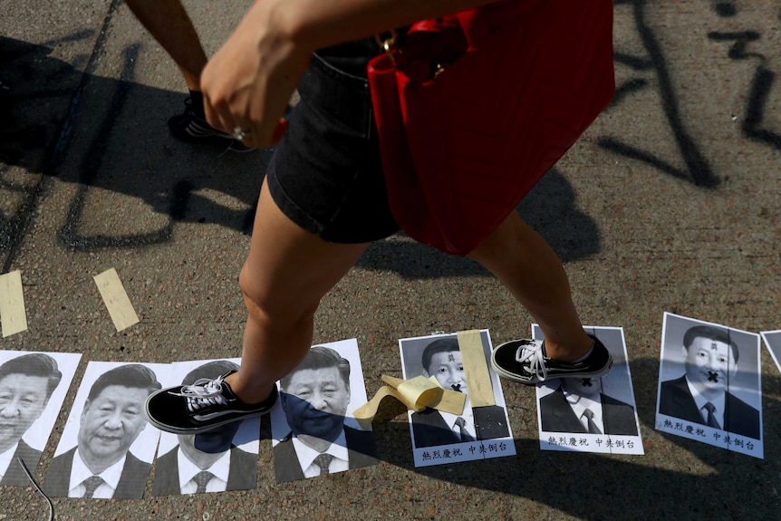 A person walks on the ground littered with portraits of Chinese President Xi Jinping.