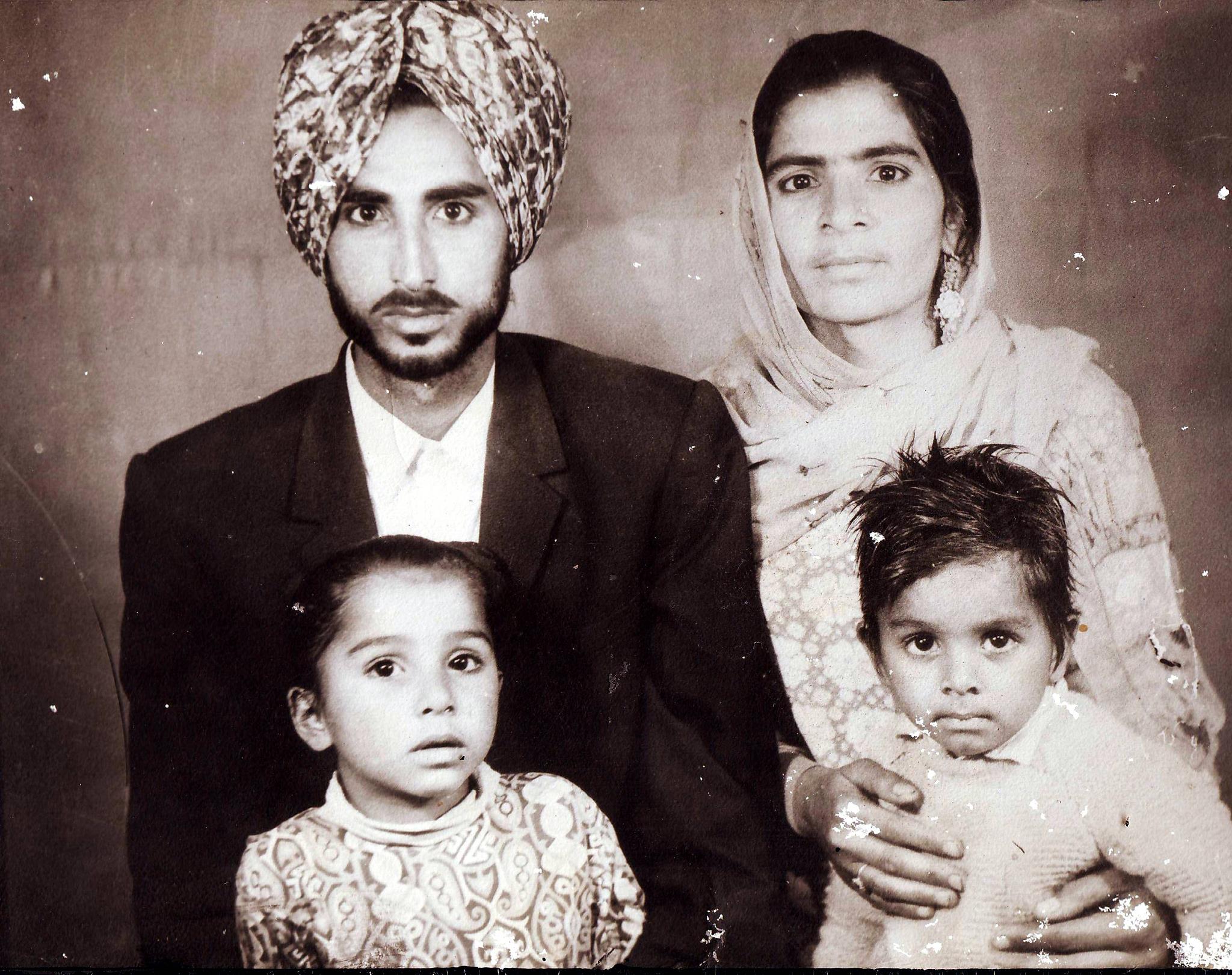A sepia photo shows a young Mintu with his parents and brother, dressed in traditional Sikhs.