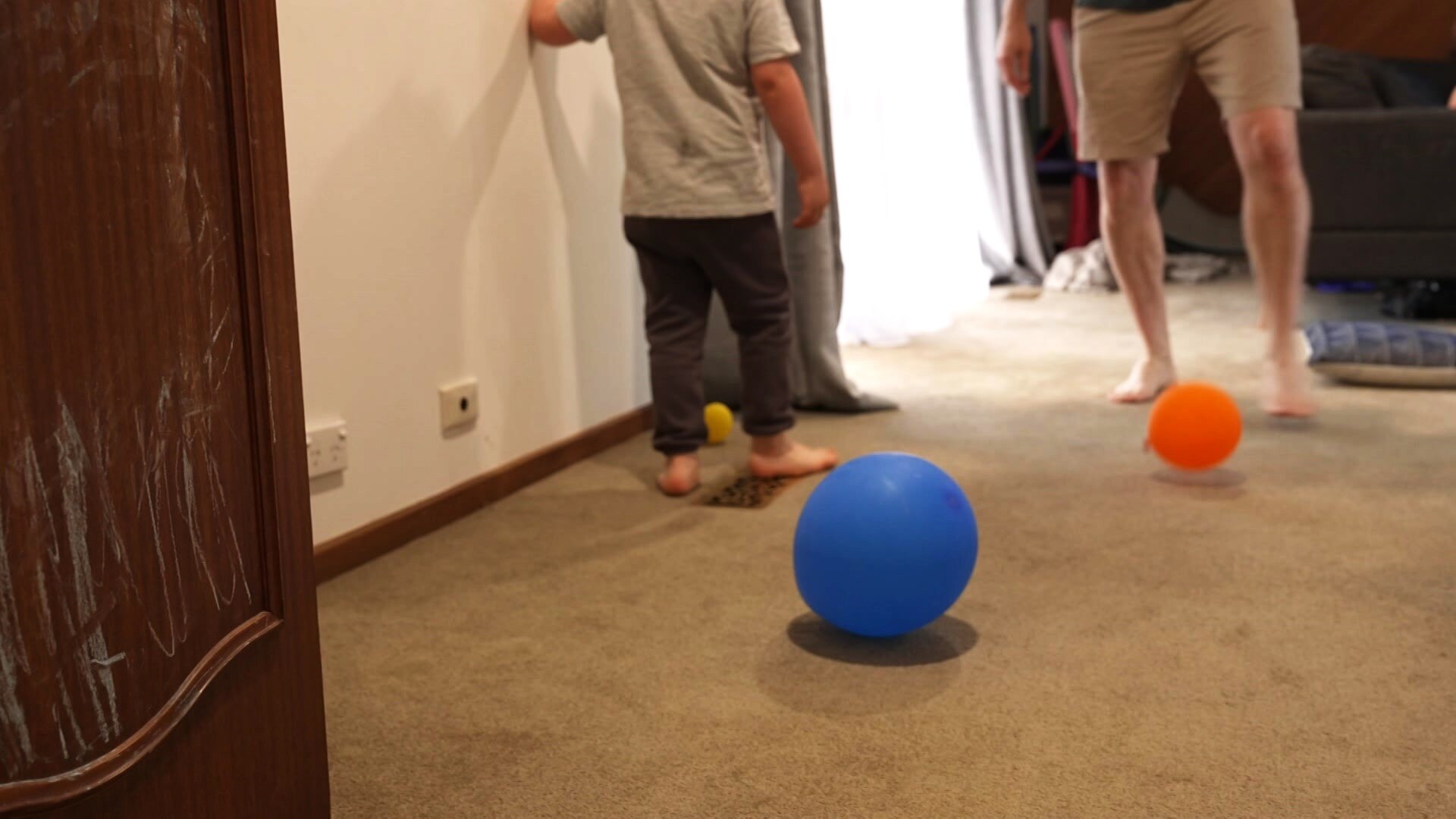 Father kicks balloons indoors with his son.