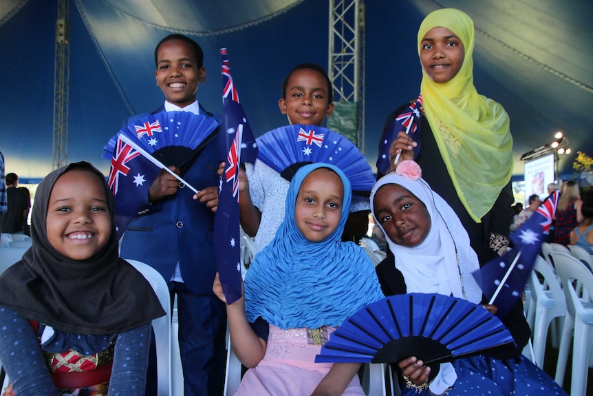 Six children waving Australian flags celebrate together at the largest Australia Day citizenship ceremony in Wanneroo.
