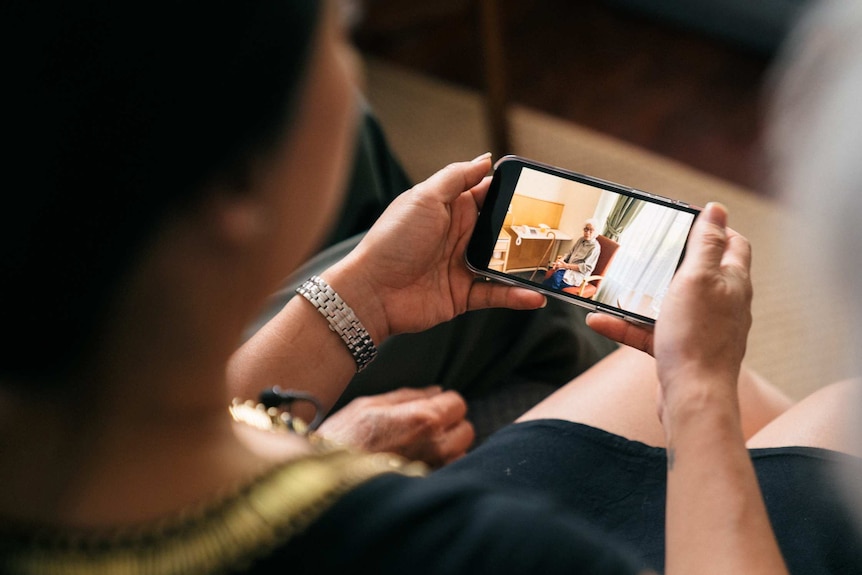 Phoebe looks at a photo of Nancy in aged care on her phone.