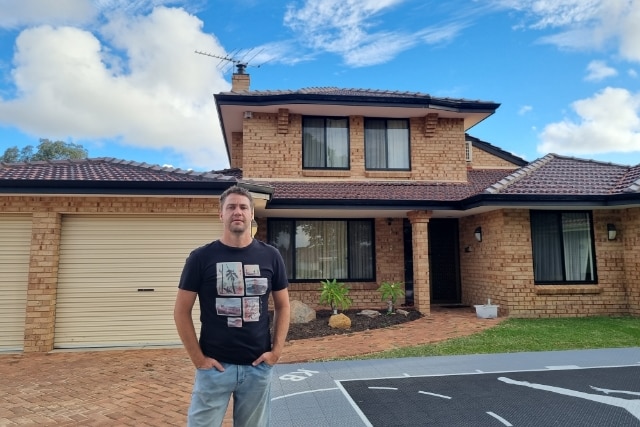 Recent home buyer Denis Barnard standing in front of a house with a blue sky behind.
