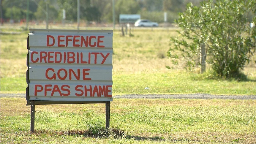 A sign reads "Defence Credibility Gone - PFAS Shame"