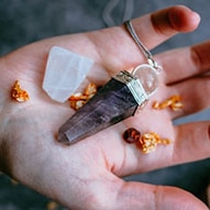 Hand holding crystals, with candle below.