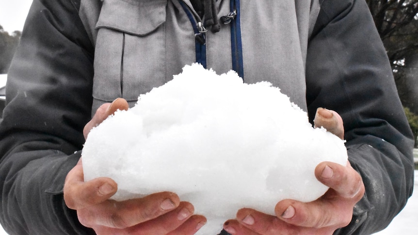 A close-up of a large clump of snow being held by someone.