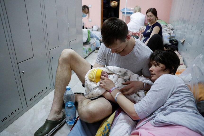 A father and mother hold their newborn in the basement of a hospital