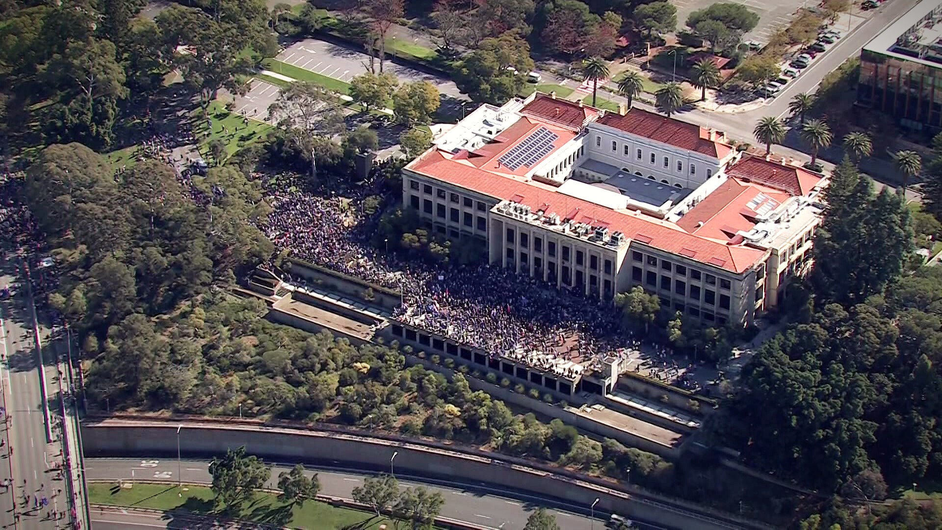 Aerial shots of a a large group of people dressed in Australian flag insignia rally