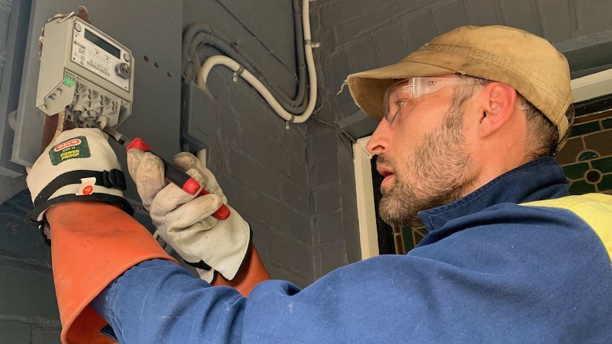 An electrician installs a new smart meter at a house in Sydney's inner-west.