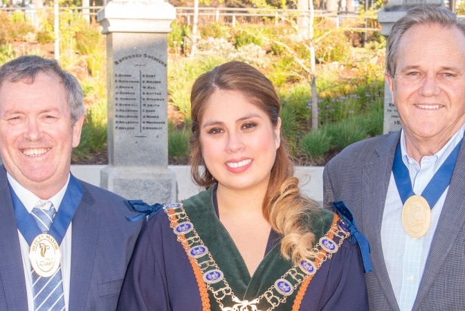 A woman wears a mayoral robe and smiles at the camera.