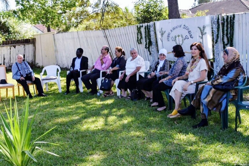 a group of people sitting on chairs in a backyard