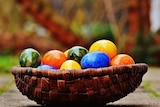 A bunch of brightly coloured eggs in a basket