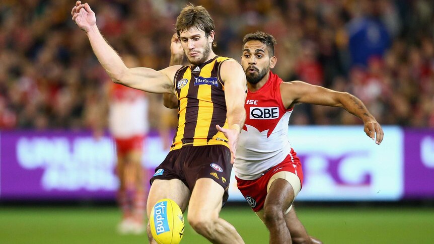 Hawthorn's Grant Birchall kicks while being tackled by Sydney's Lewis Jetta at the MCG.