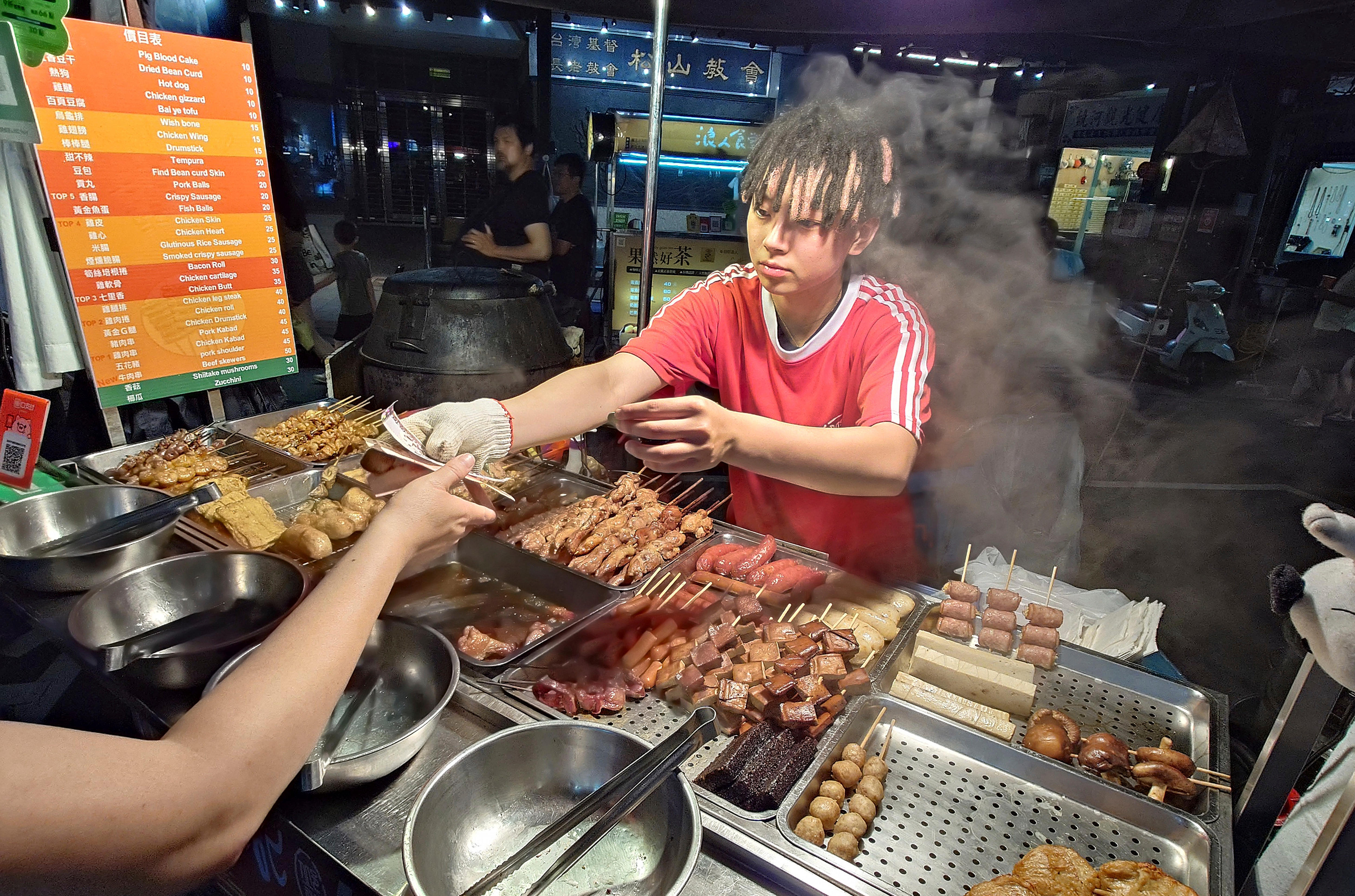 Un hombre que vende brochetas de carne a la parrilla cambia de manos a un cliente.
