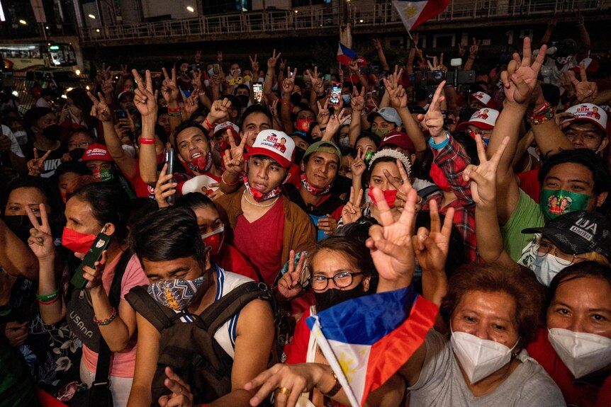 A huge crowd of people in the Philippines, many holding up two fingers