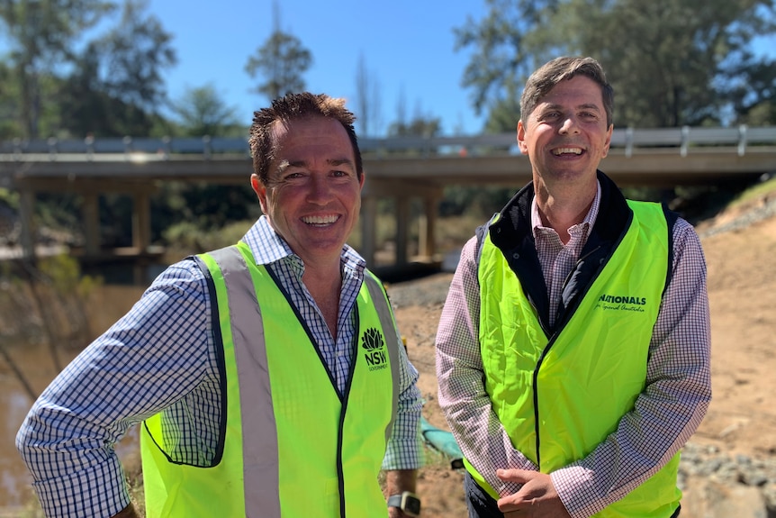 Paul Toole and David Layzell smiling wearing green vests with a bridge in the background