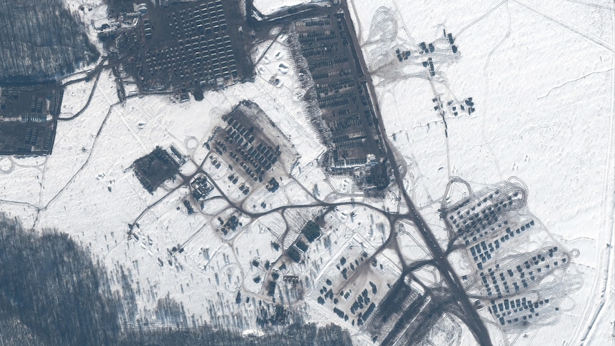 一张卫星图片上显示了俄罗斯在库尔斯克训练区部署部队和武器设备，白雪中可以看到灰绿色的方块和黑色的铁丝网