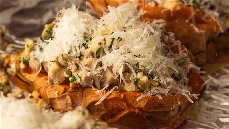 A loaded sweet potato with creamy mushroom, chicken with grated cheese on top ready to grill.