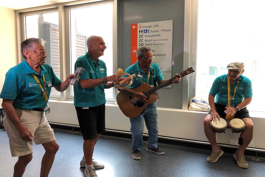 Four musicians playing their instruments as a band in the foyer of the Princess Alexandra Hospital in Brisbane.