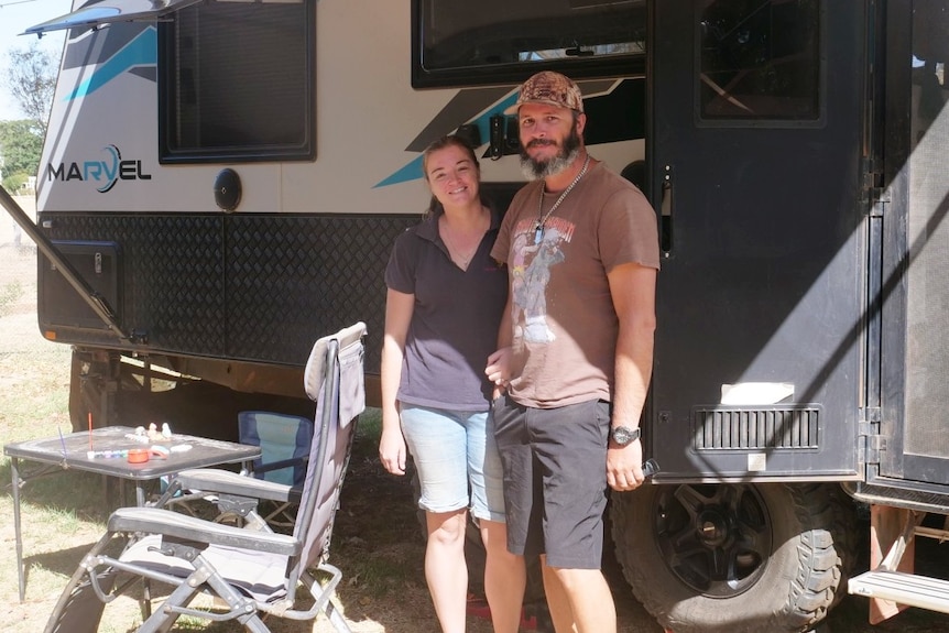 A couple stands in front of a caravan