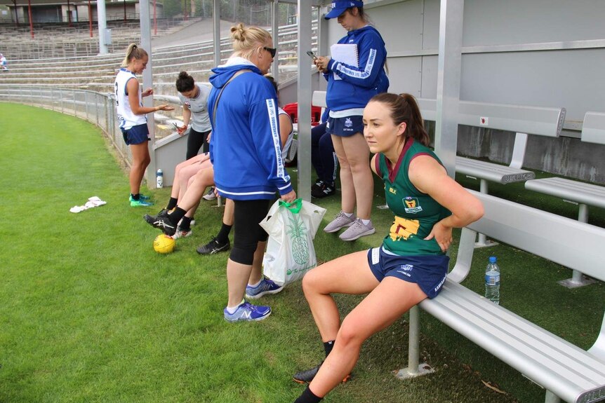 AFLW player Nicole Brenehan sits on the bench with her hands on her hips