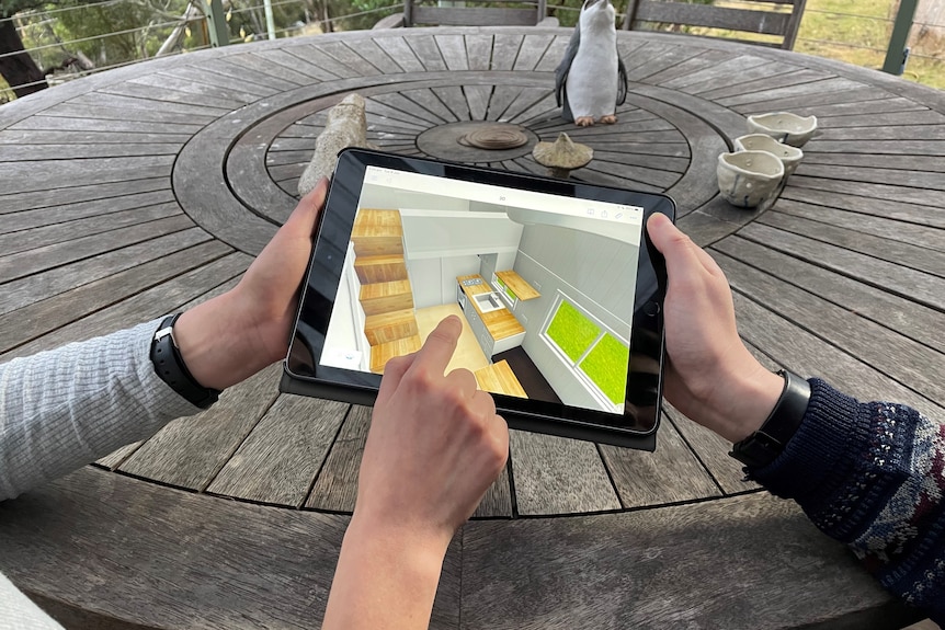 An iPad with an animated model of a kitchen on it.